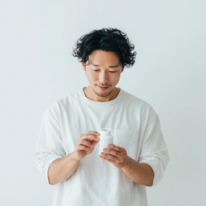 japanese_man_in_his_30s_looking_at_a_small_white_bottle_2303a066-2aa6-439d-a2c1-33662a06e96c